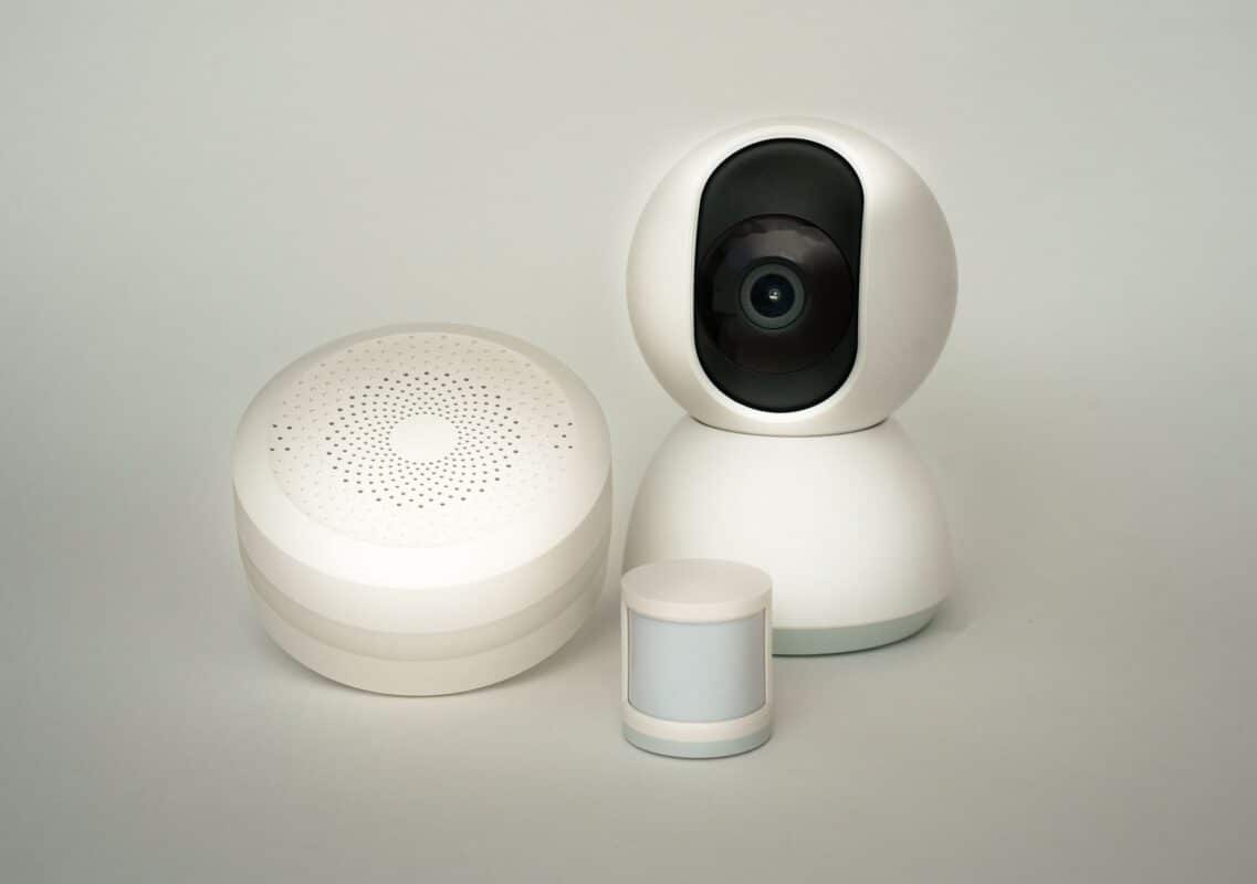Modern smart home devices including a camera and sensors on a neutral background.